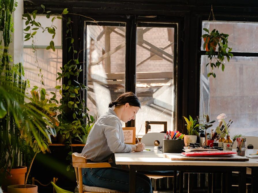 photo of woman sitting by the table while writing